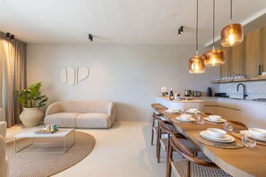 A modern kitchen with a dining area, a sofa, and a coffee table. - Dolce Vita - Tropical Poolside Paradise (Sint Michiel)