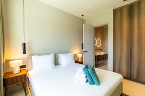 A hotel room with a bed, bedside lamps, a bathroom with a mirror and sink, and a wardrobe. - Dolce Vita - Tropical Poolside Paradise (Sint Michiel)