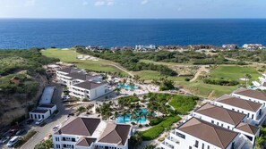 A resort with multiple buildings, a swimming pool, and a view of the ocean. - Dolce Vita - Tropical Poolside Paradise (Sint Michiel)