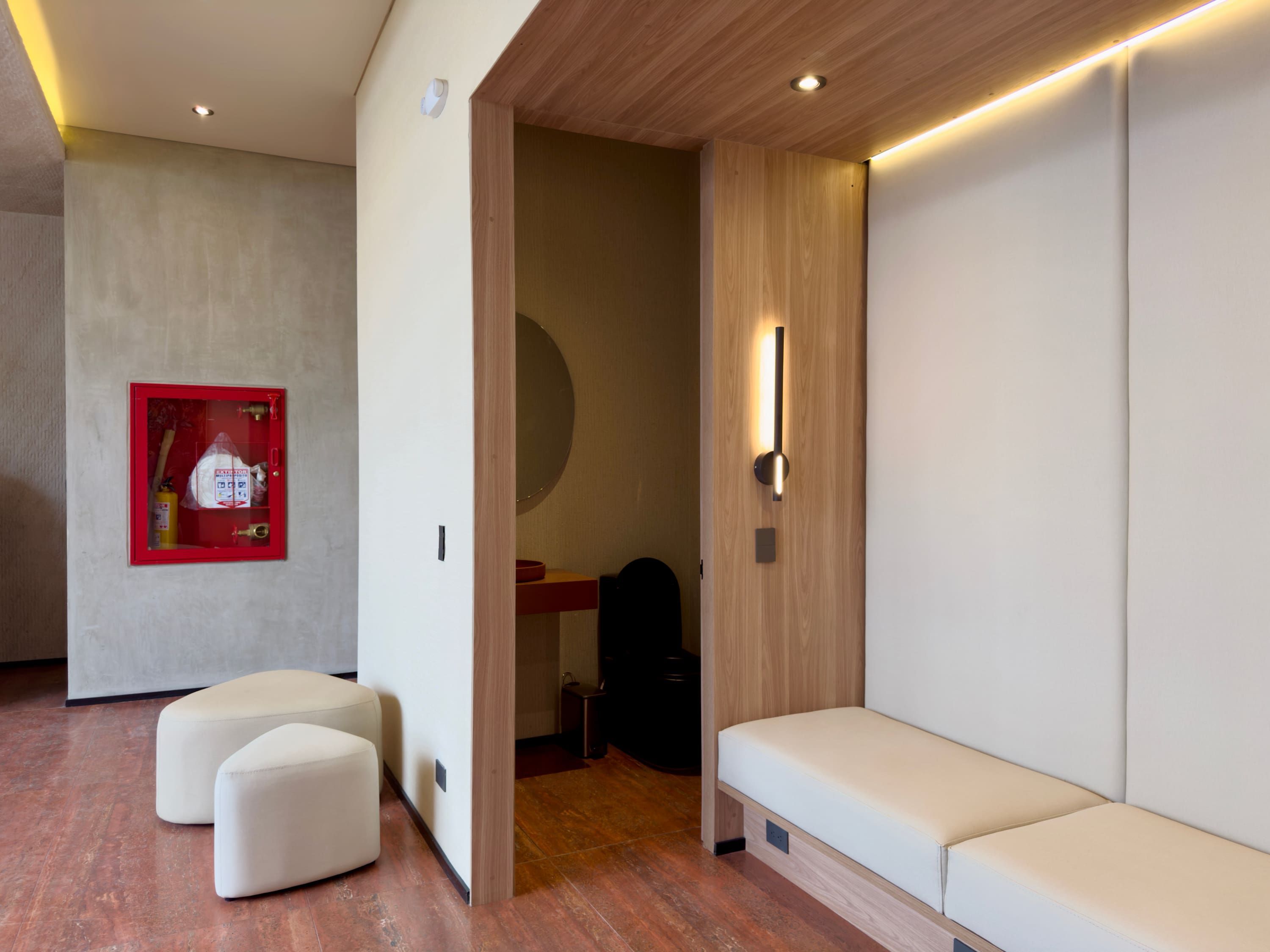 Een modern interieur met een zithoek, een rode brandblusser en een houten wand.