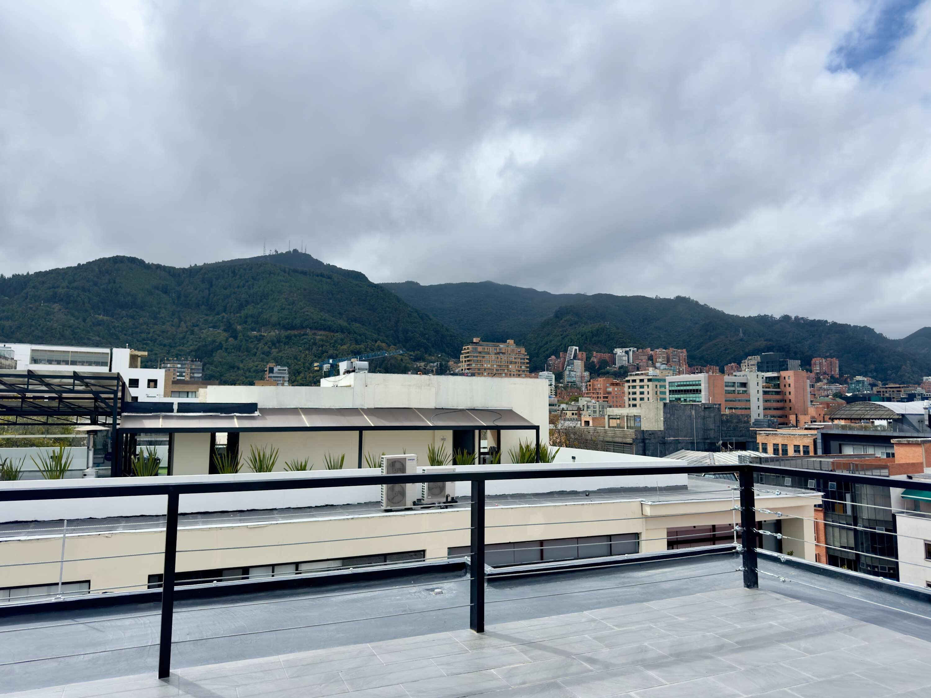 Una terraza en la azotea con vistas a un paisaje urbano y montañas.