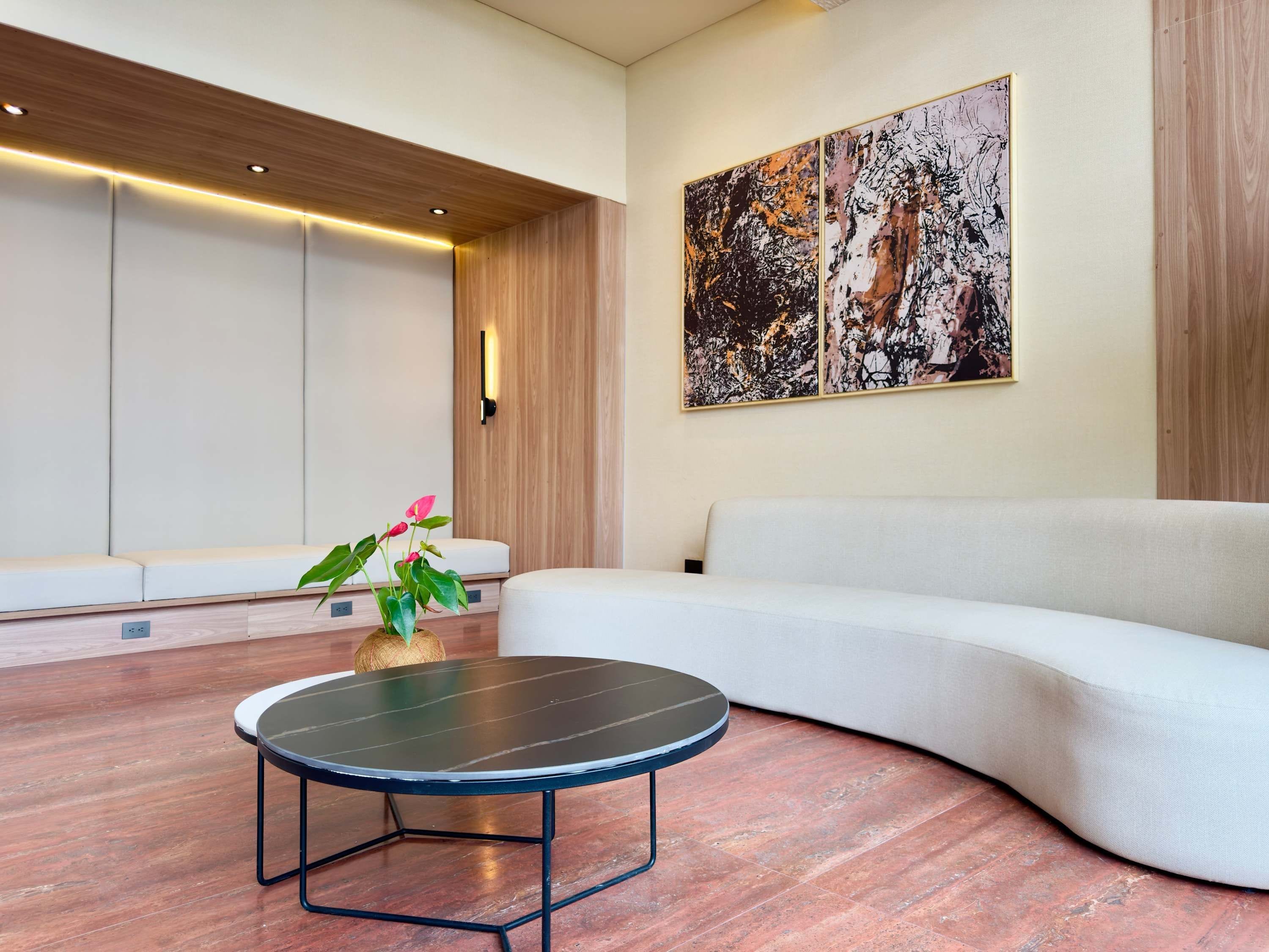 Un soggiorno moderno con un divano bianco curvo, un tavolino nero rotondo e un grande quadro astratto appeso al muro.