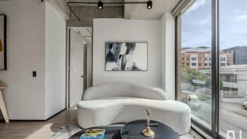 Un salon moderne avec une grande fenêtre, un canapé blanc, une table basse ronde et un lampadaire noir.