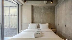 A modern bedroom with a large bed, a view of the outside, and a concrete wall. - NOK Elegant 2BR Retreat Near Parque 93 Bogota (Bogotá)