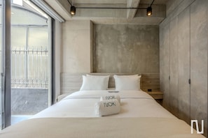 Ein modernes Schlafzimmer mit einem großen Bett und Blick nach draußen, sowie einer Betonwand.