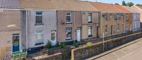 A row of terraced houses with a paved driveway and a stone wall.