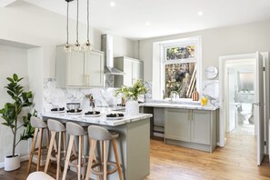 Una cocina moderna con encimera de mármol, taburetes de bar y un amplio ventanal.