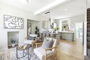 A spacious living area with a sofa, chairs, a coffee table, and a dining area with a kitchen in the background.