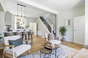 Amplia sala de estar con cocina, comedor y escalera que conduce a un nivel superior.