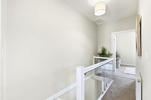 A modern interior with a glass railing, a light fixture, and a door leading to another room. - Modern 3-bed Swansea Home Parking (Swansea)