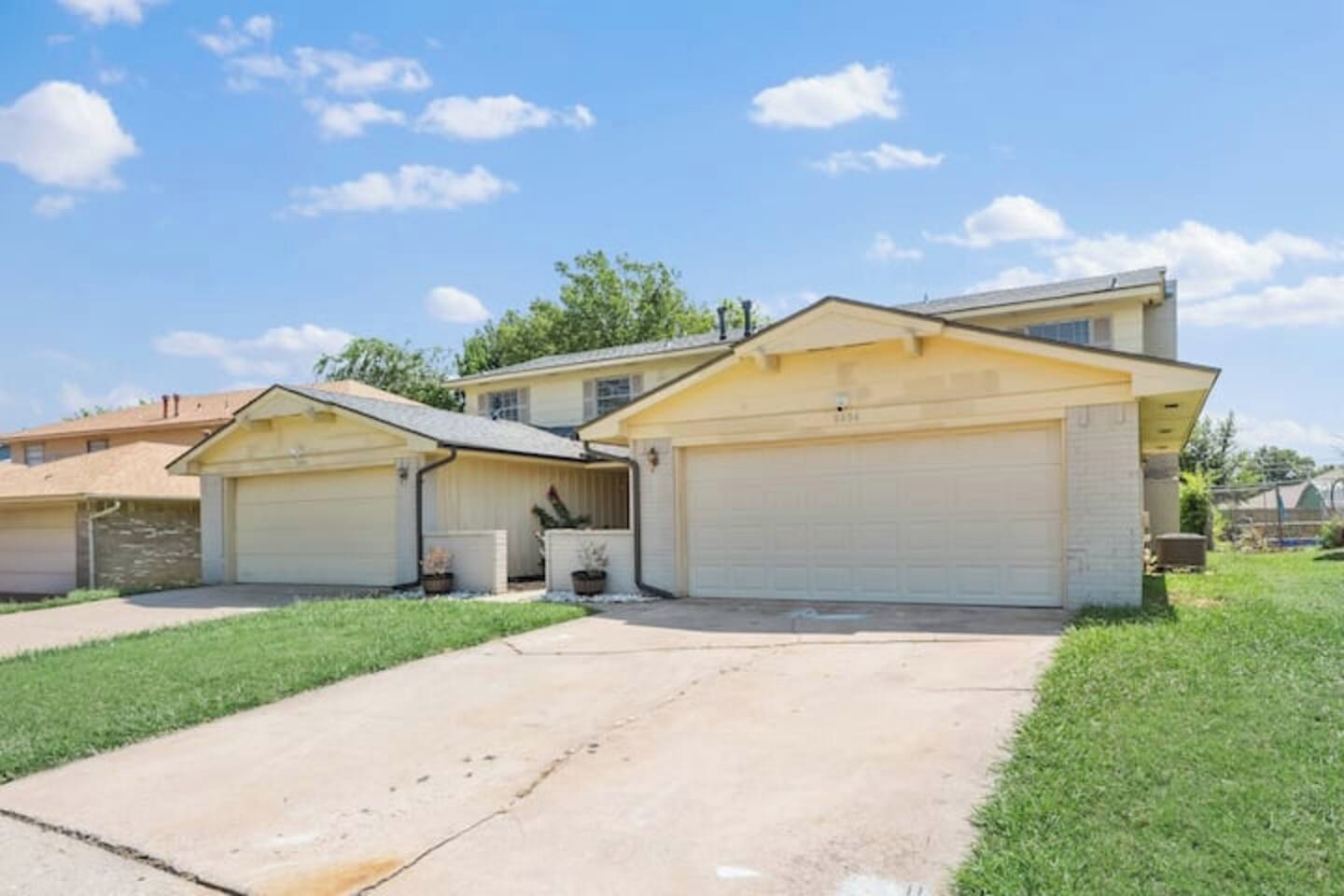 A two-story house with a garage, a covered driveway, and a well-maintained lawn.