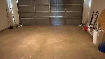 A garage with a concrete floor, a closed garage door, and a light fixture on the ceiling.