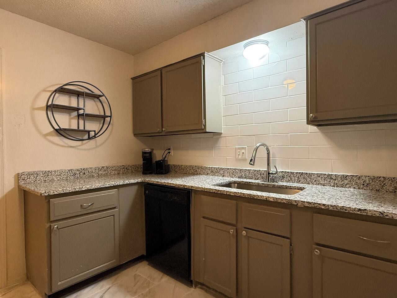 A compact kitchen with a dishwasher, a sink, and a coffee maker.