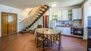 A kitchen with a dining table, chairs, a stove, and a staircase. - Il Sentiero del Riccio (Sicignano degli Alburni)