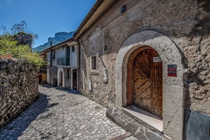 A cobblestone street with historic stone buildings, a wooden door, and a sign indicating a fire alarm system.
