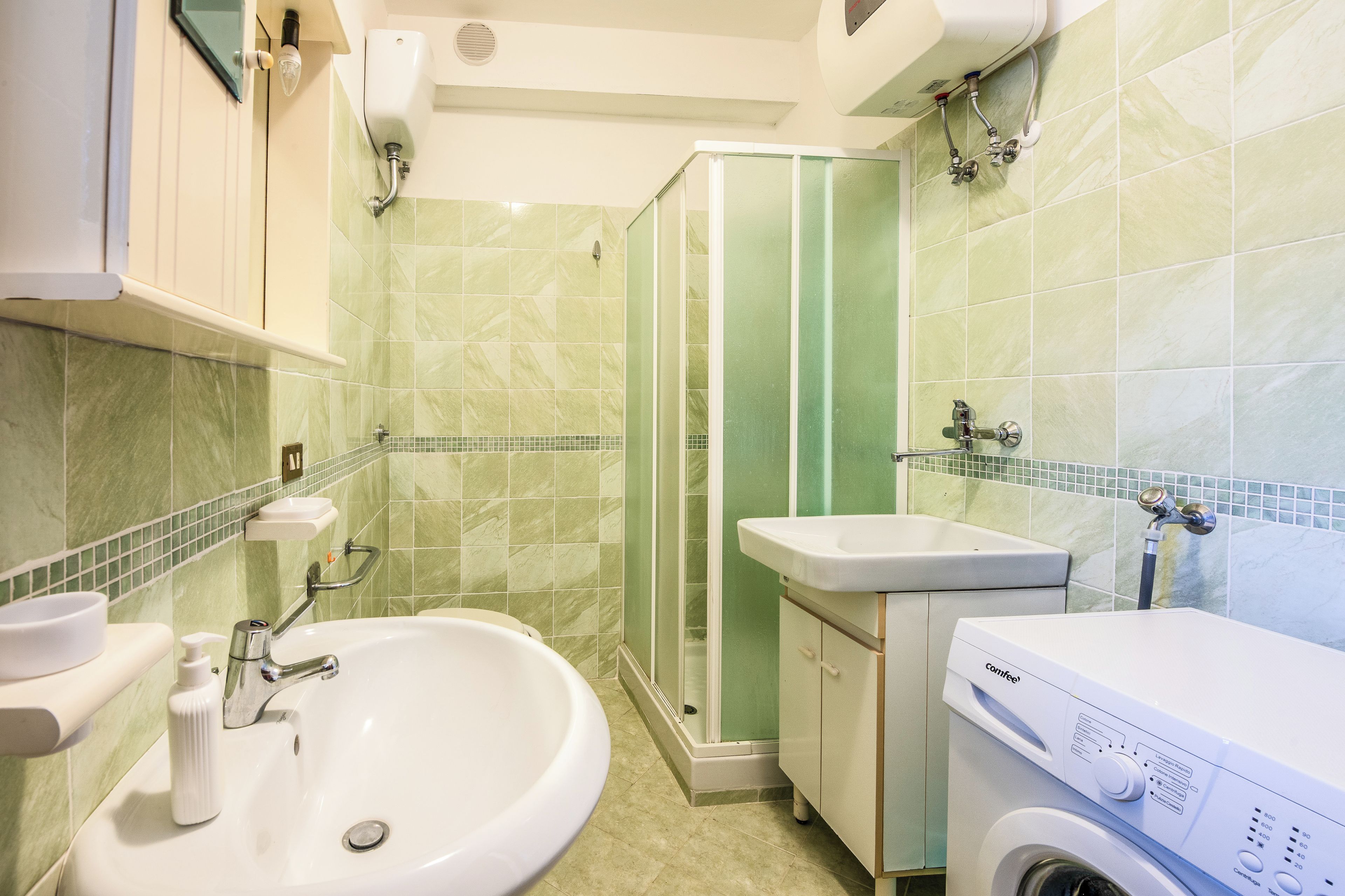 Ein Badezimmer mit Waschbecken, Dusche und Waschmaschine.