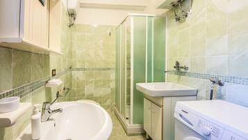 Ein Badezimmer mit Waschbecken, Dusche und Waschmaschine.
