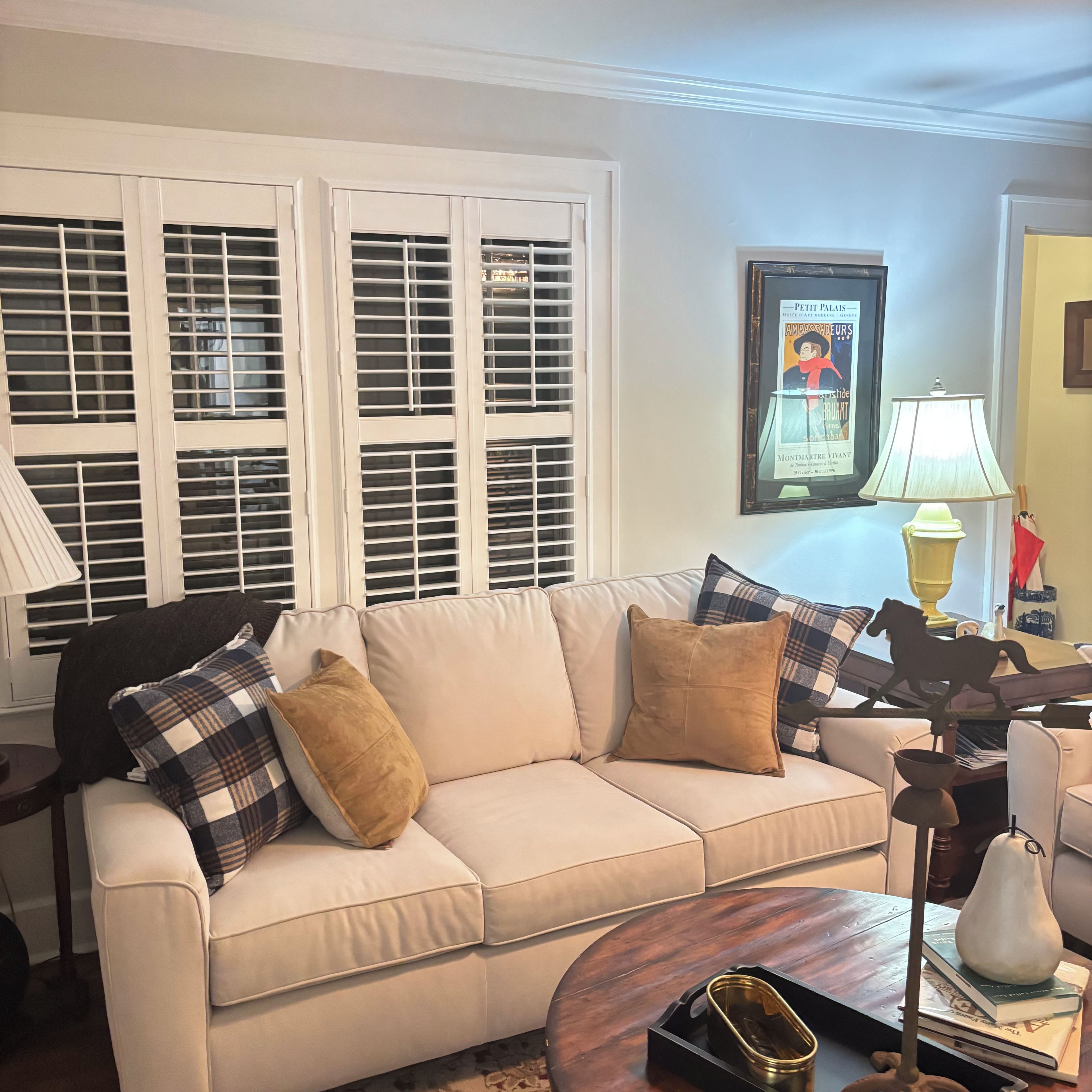 A living room with a beige sofa, a coffee table, and a framed poster on the wall.