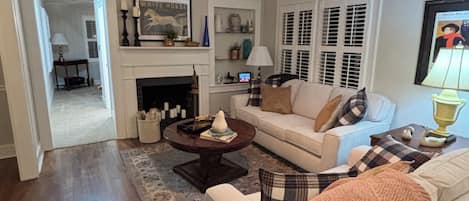 A living room with a fireplace, a sofa, a coffee table, and a chandelier.
