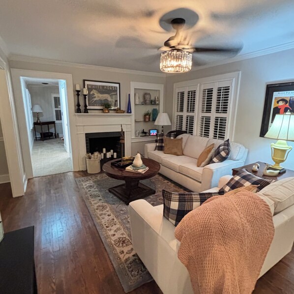 A living room with a fireplace, a sofa, a coffee table, and a chandelier.