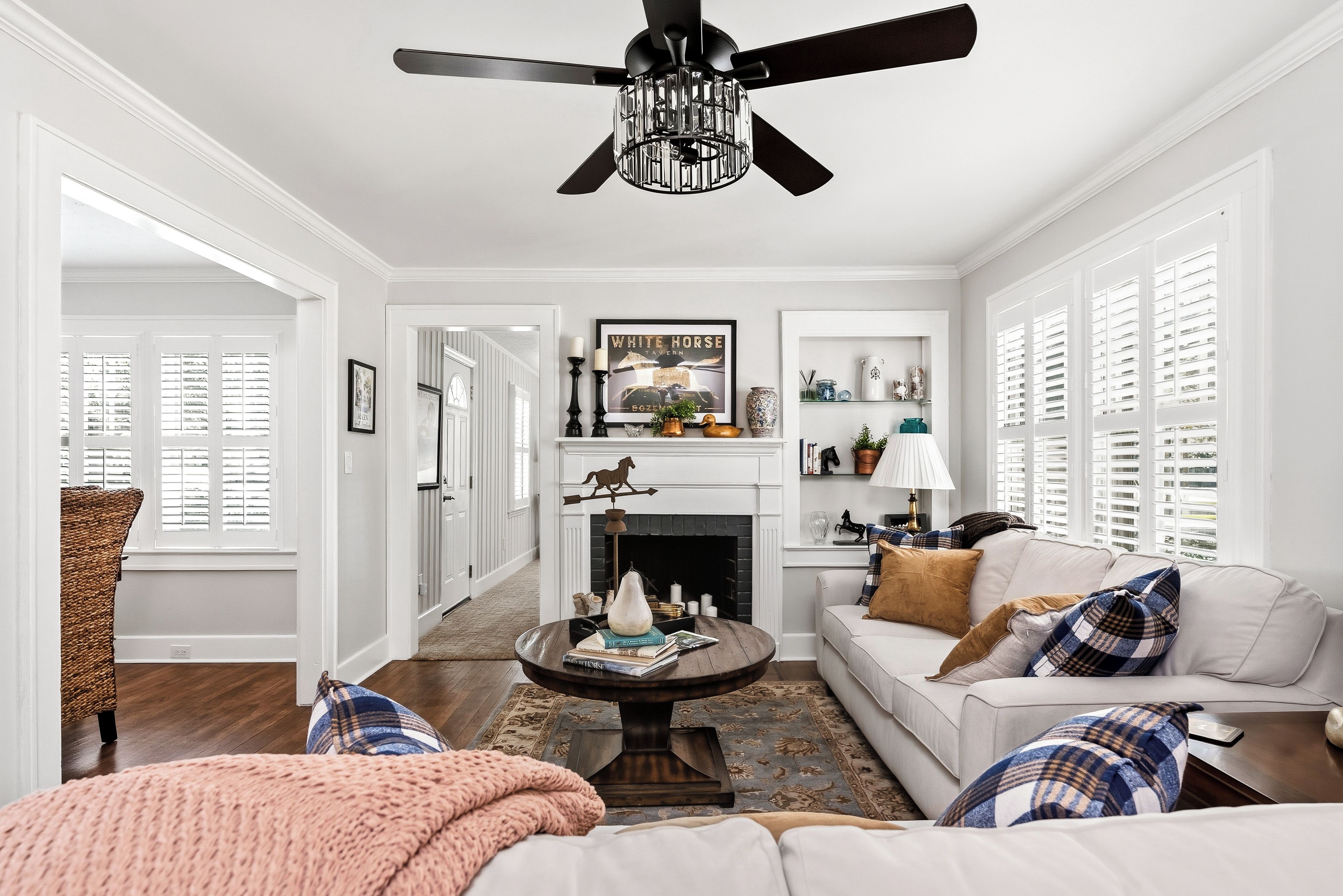 A well-lit living room with a fireplace, a ceiling fan, and a cozy seating area.