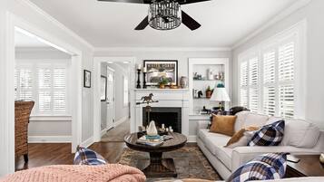 A well-lit living room with a fireplace, a ceiling fan, and a cozy seating area.