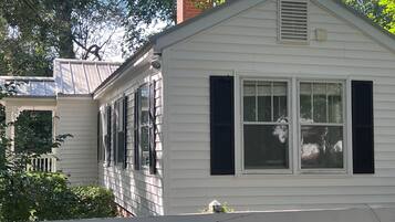 A white single-story house with dark shutters, a visible chimney, and a white picket fence.