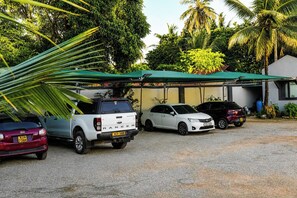 A parking area with three cars parked under a green canopy. - Quaint 1-bedroom apartment in Ukunda perfect for relaxing stays (Ukunda)