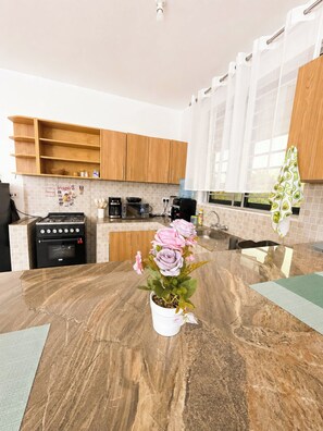 A modern kitchen with wooden cabinets, a gas stove, a microwave, and a sink. - Quaint 1-bedroom apartment in Ukunda perfect for relaxing stays (Ukunda)