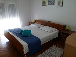 A neatly made bed with white and blue bedding, wooden headboard, and two bedside tables with lamps. - Big apartment with large terrace & great sea view, close to the beach (Arbanija)