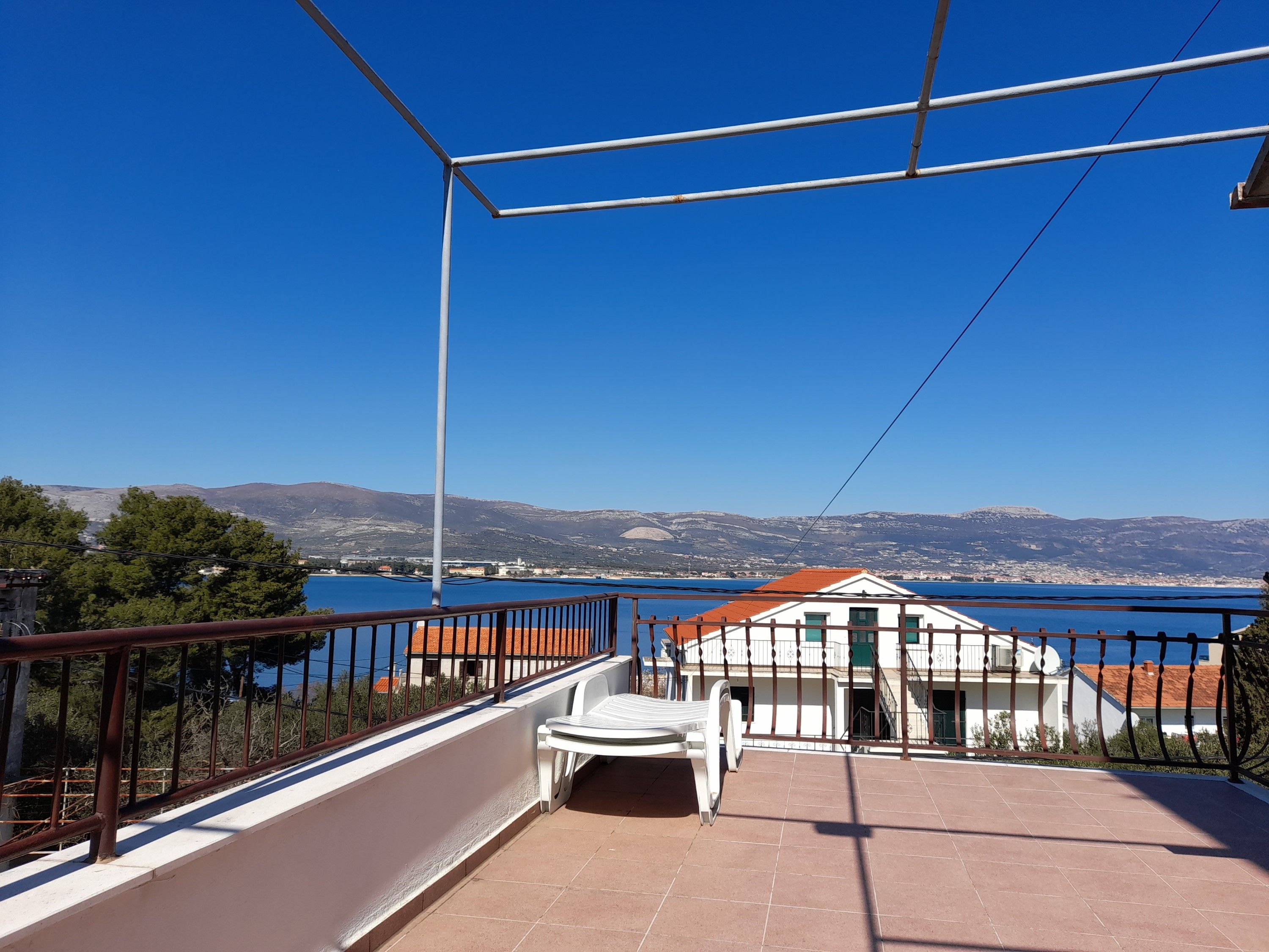 A balcony with a view of a body of water and distant mountains.