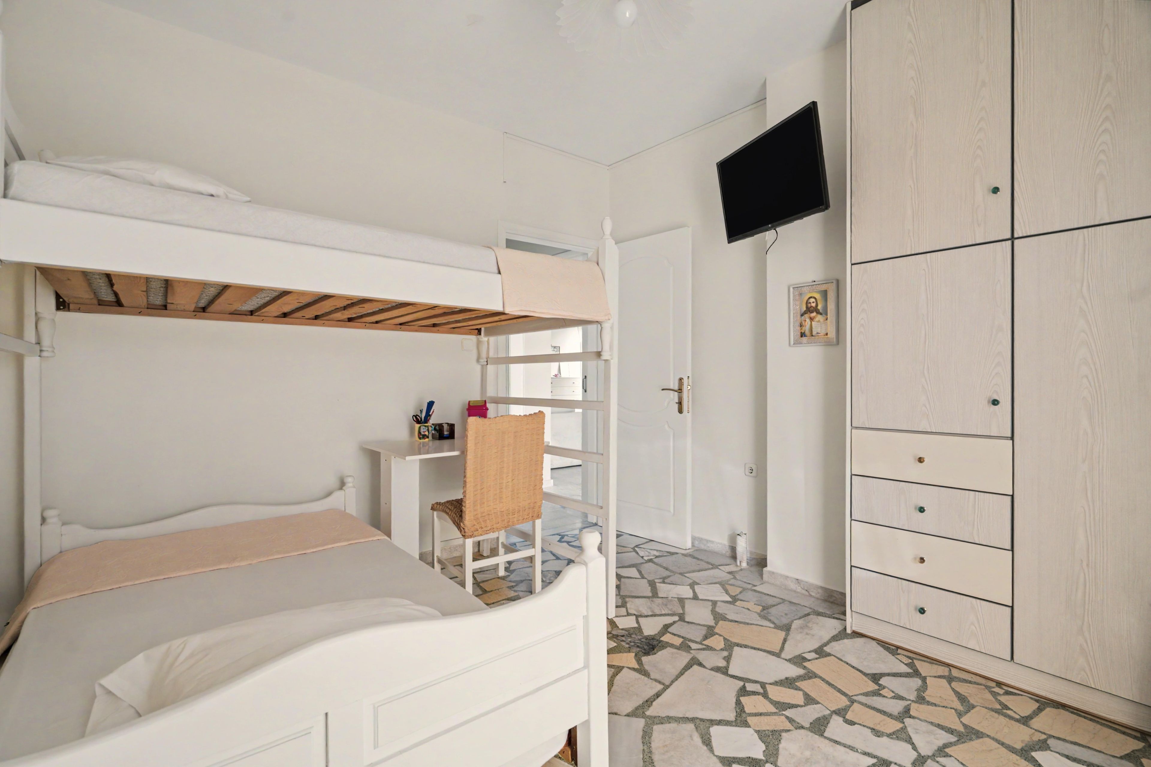 A bedroom with bunk beds, a wardrobe, a television, and a tiled floor.
