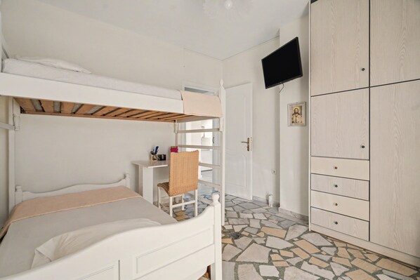 A bedroom with bunk beds, a wardrobe, a television, and a tiled floor.