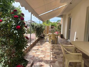 An outdoor patio with a table and chairs, surrounded by a stone floor and a pergola with climbing plants. - Blossom Beachfront House with Private Terrace, Wi-Fi, and Air Conditioning (Κουρούτα)