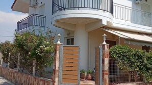 Ein zweistöckiges Haus mit einem gebogenen Balkon, Steinmauern und Blumentöpfen.