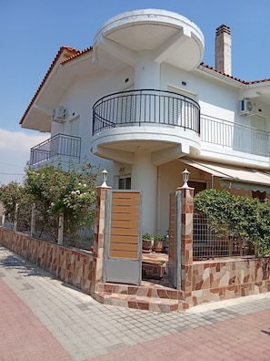 A two-story house with a curved balcony, stone walls, and potted plants. - Blossom Beachfront House with Private Terrace, Wi-Fi, and Air Conditioning (Κουρούτα)