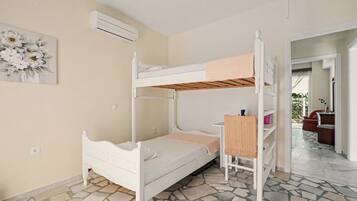A bunk bed room with a white bed, a small table, and a chair.