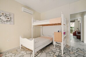 A bunk bed room with a white bed, a small table, and a chair.