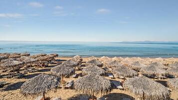 Une plage avec des parasols en chaume et des chaises longues.