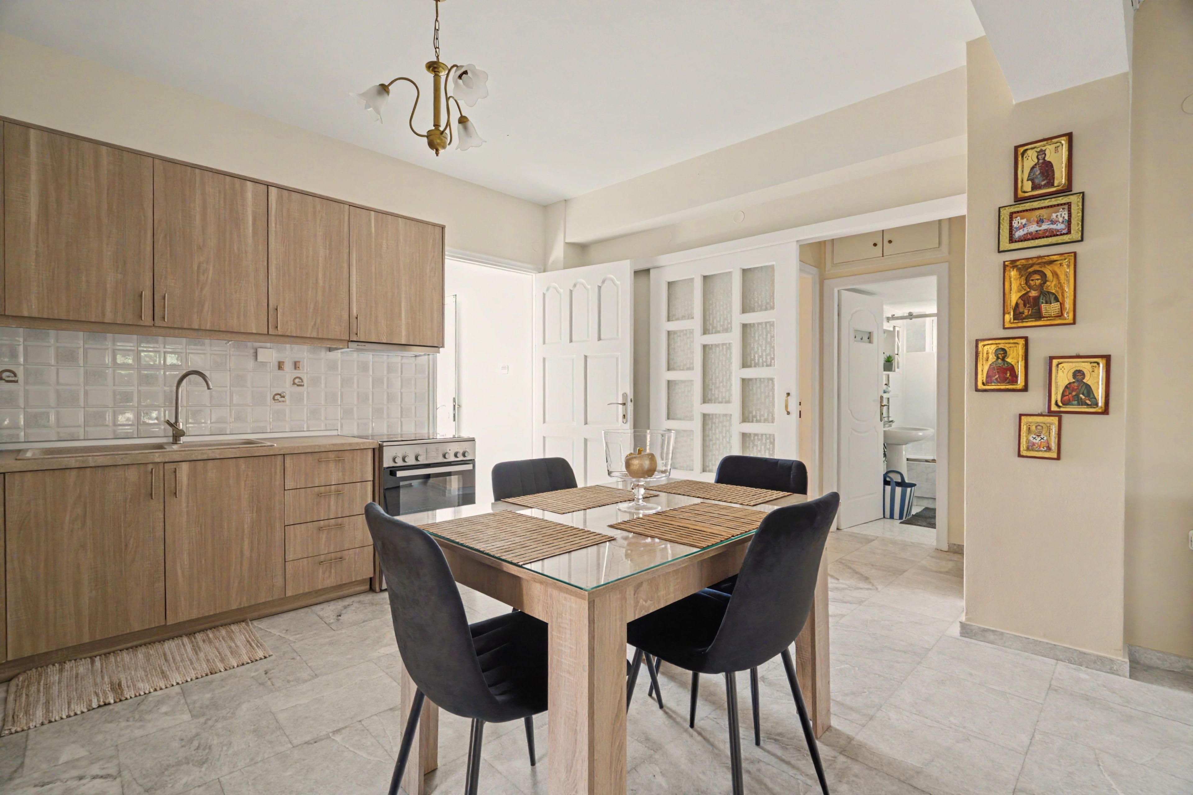 Une cuisine moderne avec des meubles en bois, une table à manger avec des chaises et un lustre.