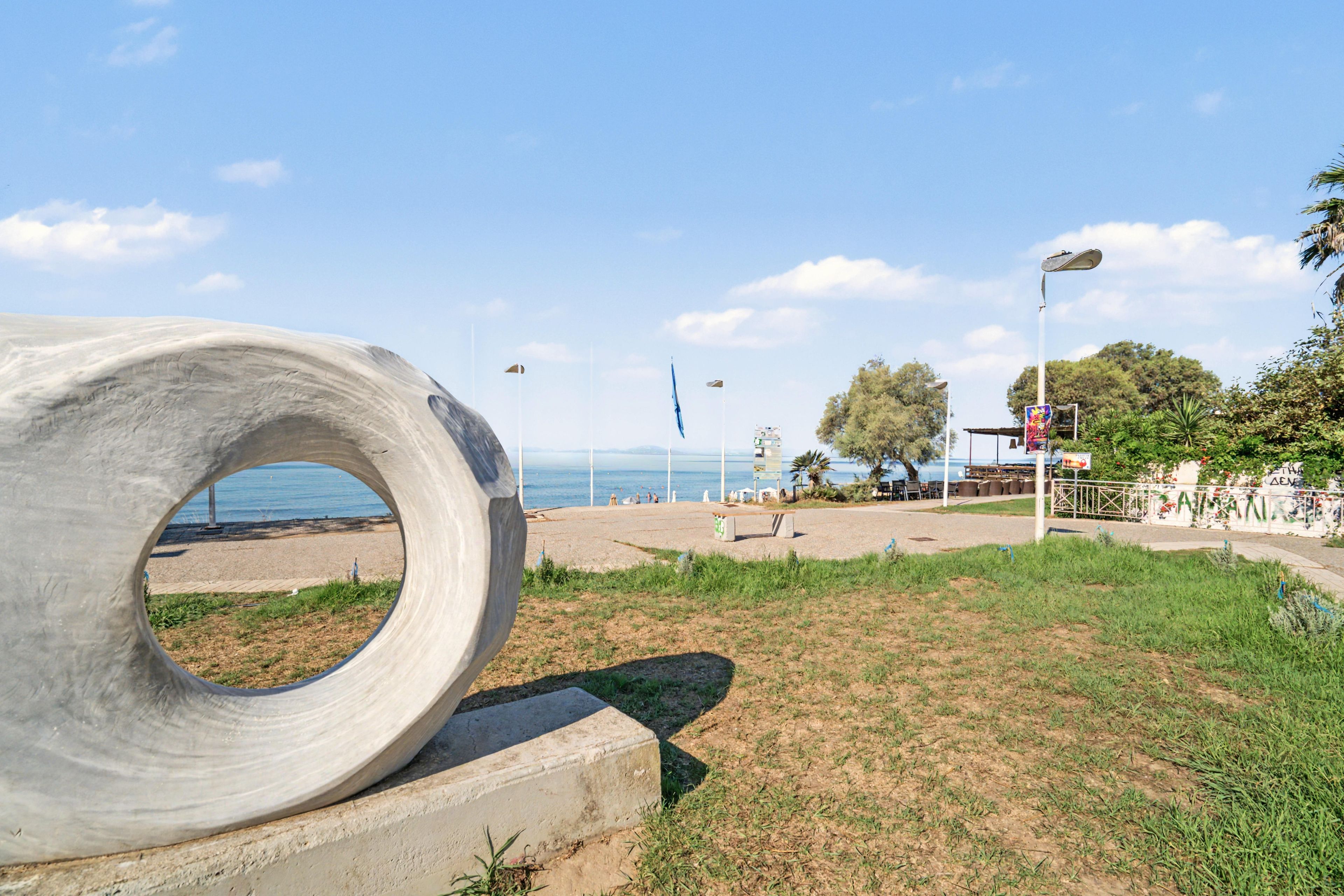 A concrete sculpture on a grassy area with a beach and ocean in the background.