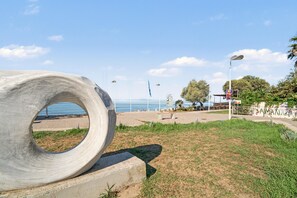 A concrete sculpture on a grassy area with a beach and ocean in the background.