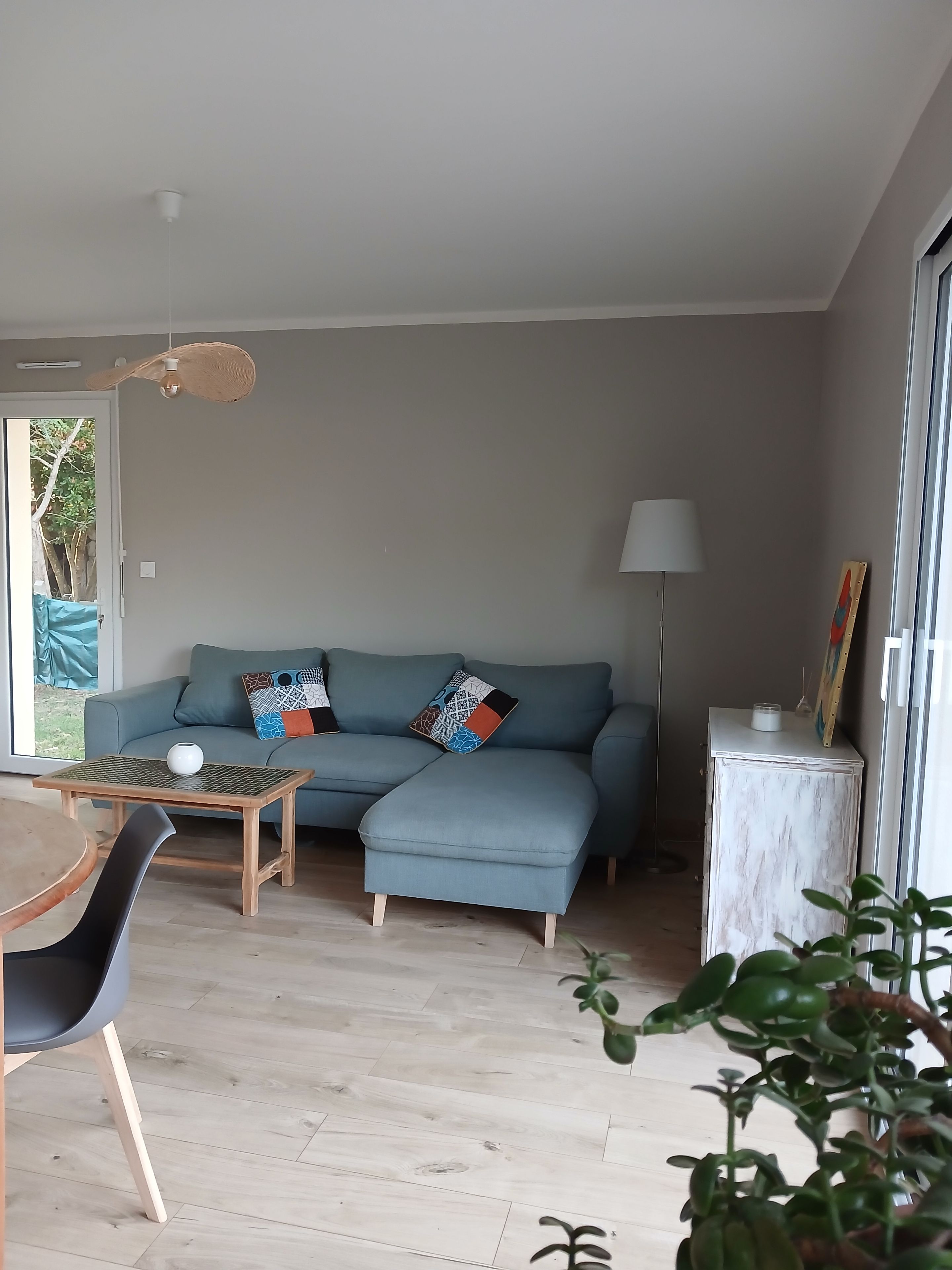 Uma sala de estar com sofá, mesa, luminária e aparador.
