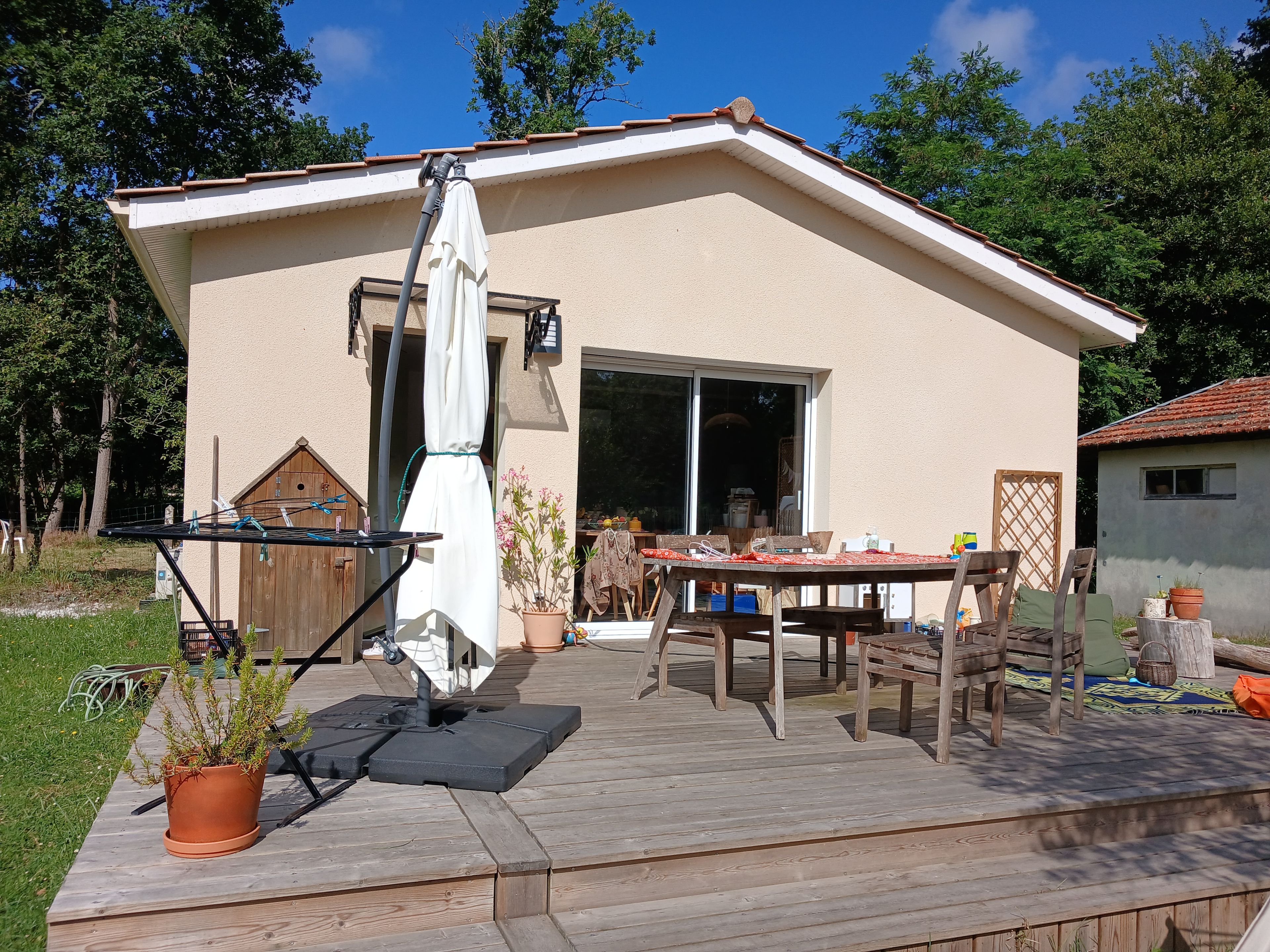 A patio with a table and chairs, a drying rack, and a potted plant.
