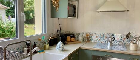 A kitchen with a sink, stove, and a window overlooking a garden.