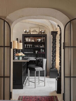 Une cuisine dotée d’un îlot central, de tabourets de bar, d’une colonne décorative et d’un tapis à motifs.