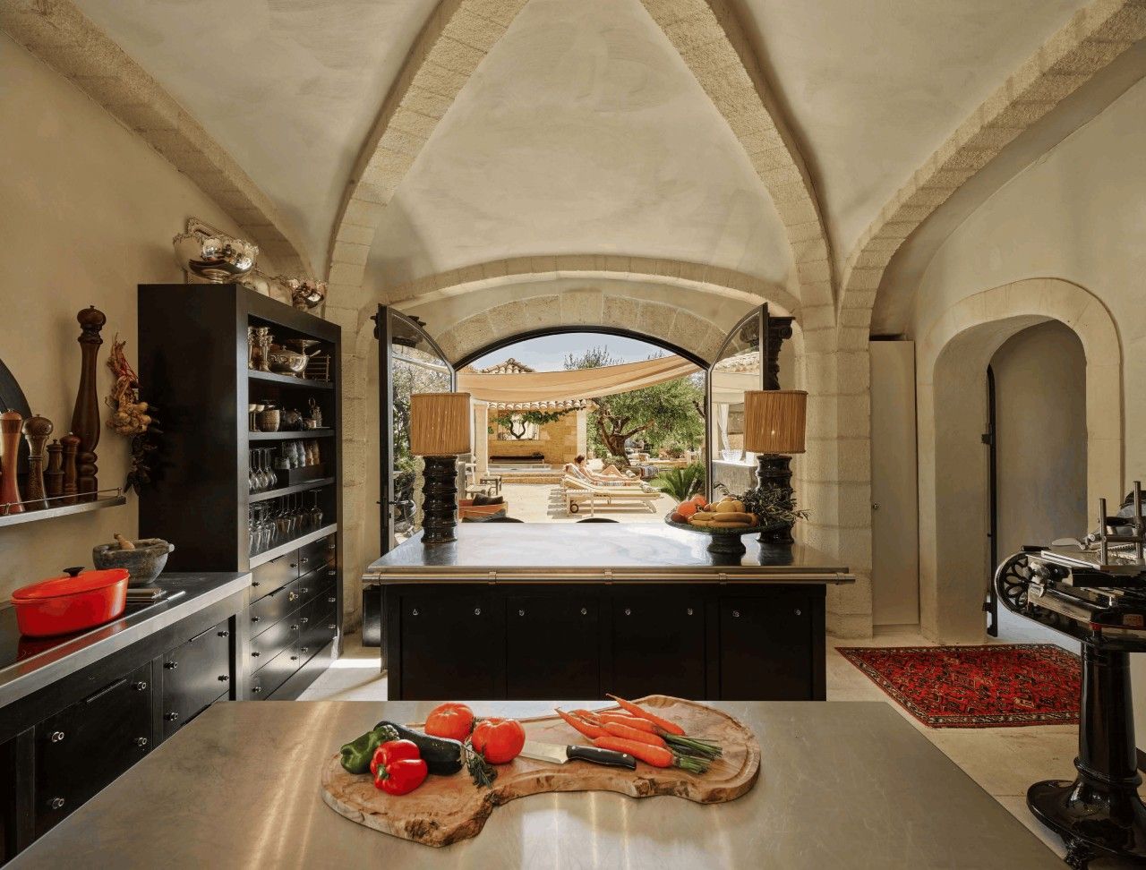 A kitchen with a central island, open shelving, and a view of a patio area.