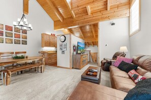 A spacious living area with a wooden ceiling, a dining table, a sofa, and a television. - Indian Hills Charming Townhome 3 Bedroom Townhouse (Truckee)