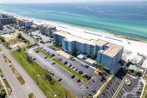 Luftaufnahme eines Hotels mit Parkplatz, Strand und Meerblick.