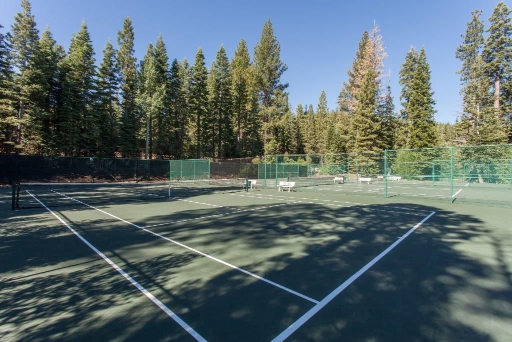 Una cancha de tenis al aire libre rodeada de árboles altos.
